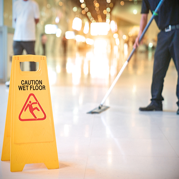 day porter using flat  mop in common area with hazard sign