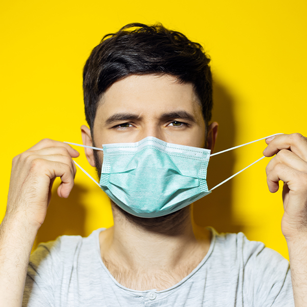 Man holding mask ear loops.